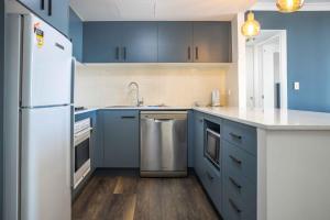 a kitchen with blue cabinets and a white refrigerator at Central 1-Bed with Parking, Pool, Sauna & Gym in Sydney