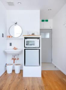 a white kitchen with a sink and a microwave at ぷふか浅草 in Tokyo