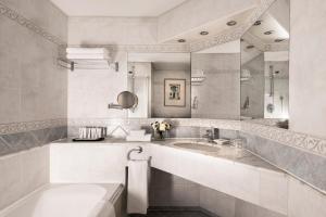 a bathroom with a sink and a tub and a mirror at Corinthia St George's Bay in St. Julianʼs