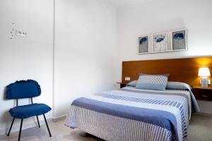 a bedroom with a bed and two blue chairs at Casa Buganvilla in Conil de la Frontera +20 photos