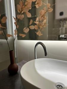 a vase with flowers on a counter next to a sink at Apartman Tara in Subotica