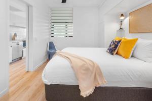 1 dormitorio con 1 cama blanca grande con almohadas amarillas en Spacious 2-Bed Unit With Balcony Next to The Gabba en Brisbane