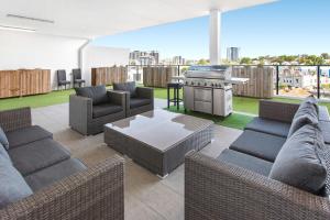a patio with couches and a table and a grill at Spacious 2-Bed Unit With Balcony Next to The Gabba in Brisbane