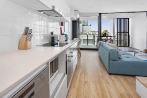 a kitchen and living room with a blue couch at Spacious 2-Bed Unit With Balcony Next to The Gabba in Brisbane