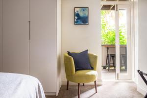 1 dormitorio con silla amarilla y almohada azul en Historic Boutique Apartment Steps From Everything, en Sídney