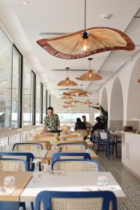リミニにあるHotel Albatrosの背景の男性とテーブルと椅子が備わるレストラン