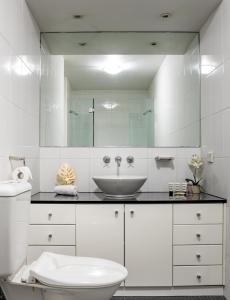 a white bathroom with a sink and a toilet at Stylish Studio With Pool & Gym in Heart of Sydney in Sydney