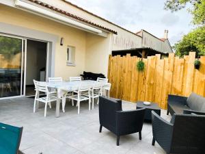a patio with a table and chairs and a fence at Entre mer et foret 1 in Jard-sur-Mer
