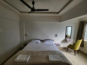 1 dormitorio con 1 cama grande y 1 silla amarilla en Palm Crest The Colva Diaries, en Colva