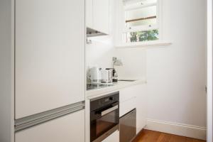 eine Küche mit weißen Schränken und einem Glaskühlschrank in der Unterkunft Boutique Studio with Balcony in Perfect Location in Sydney