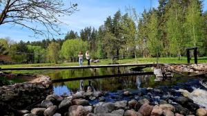 two women walking across a bridge over a river at Pakalnės sodyba in Skverbai