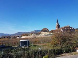 ein LKW, der auf einem Feld mit einer Kirche parkt in der Unterkunft Le clocher aux cigognes au village de Bergheim in Bergheim