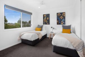 a bedroom with two beds and a window at Charming 3-Bed House with Patio near Sport Stadium in Brisbane