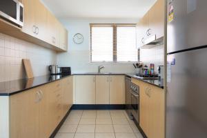 a large kitchen with wooden cabinets and a sink at Chic Unit with Rooftop Terrace near Sights & Shops in Sydney