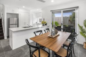 a kitchen and dining room with a wooden table and chairs at Charming 3-Bed House with Patio near Sport Stadium in Brisbane