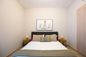 アブダビにあるF1 Dreamstay 1bhk Gym Poolのベッドルーム1室(白い大型ベッド1台、テーブル2台付) +26枚の写真