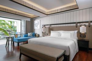- une chambre avec un grand lit blanc et une chaise bleue dans l'établissement Melia Koh Samui, à Choeng Mon Beach