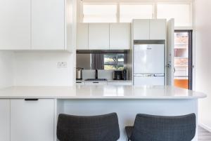 una cucina con armadi bianchi e piano di lavoro bianco di Comfy Balcony Studio near Parks, Shopping & Dining a Sydney