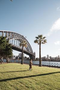 Una donna che cammina in un parco di fronte a un ponte di Comfy Balcony Studio near Parks, Shopping & Dining a Sydney