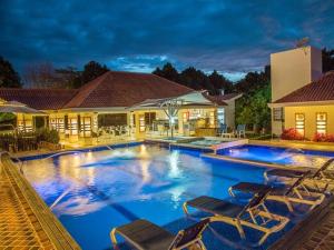 a swimming pool with chairs and a house at Hotel Boutique Duranta in Villavicencio