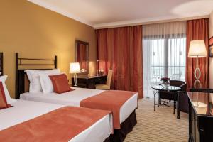 a hotel room with two beds and a desk at Corinthia St George's Bay in St. Julianʼs