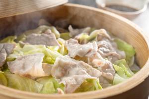 a wooden bowl of food with chicken and lettuce at KAMENOI HOTEL Kusatsu Yubatake in Kusatsu