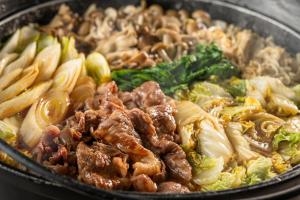 a pan full of food with meat and vegetables at KAMENOI HOTEL Kusatsu Yubatake in Kusatsu