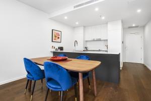 a kitchen with a wooden table and blue chairs at Boutique Unit with Huge Terrace near Cafes & Shops in Kingston 