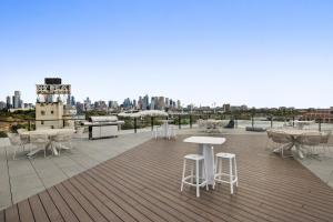 a rooftop with tables and chairs and a city skyline at Modern, Executive 1 Bedroom Apartment With Balcony in Melbourne