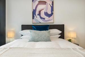 a bedroom with a bed with a painting above it at Modern, Executive 1 Bedroom Apartment With Balcony in Melbourne