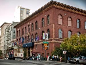 un gran edificio de ladrillo en una calle de la ciudad con gente de pie fuera en University Club of San Francisco, en San Francisco