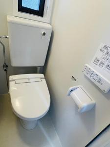 a bathroom with a white toilet and a paper dispenser at LIONS YONEGAHAMA l 米が浜通 in Yokosuka