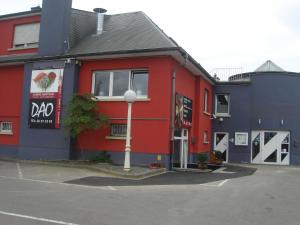 een rood en blauw gebouw met een parkeerplaats bij Hotel Restaurant Dao in Foetz
