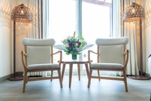 two chairs and a table with a vase of flowers at Beach Walk Boutique Jumeirah in Dubai