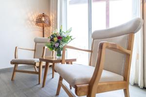 a room with two chairs and a table with a vase of flowers at Beach Walk Boutique Jumeirah in Dubai