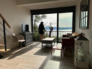 a woman looking out the window of a living room at Les Marines du Soleil - Vue Mer in Patrimonio