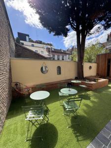 a patio with tables and chairs and a tree at Victorias House Suite in Lille