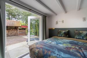 een slaapkamer met een bed en een groot raam bij PRIVÉ IN EEN BOSRIJKE OMGEVING Welkom bij gastenverblijf het ontsnapte schaap in Jubbega in Jubbega-Schurega