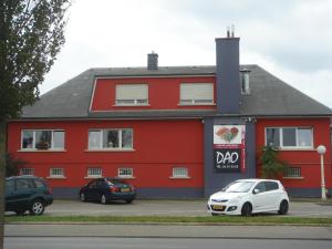 a red building with a white car parked in front of it at Hotel Restaurant Dao in Foetz