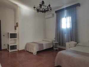 Un dormitorio con 2 camas y una ventana con una lámpara de araña. en Cortijo el Morisco., en Espera