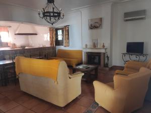 salon z żółtymi krzesłami i kominkiem w obiekcie Cortijo el Morisco. w mieście Espera