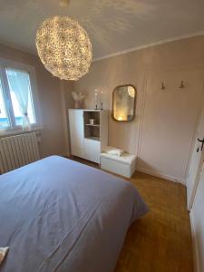 a bedroom with a large white bed and a chandelier at Chez Tad Kozh Maison familiale in Paimpol