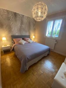 a bedroom with a large bed and a chandelier at Chez Tad Kozh Maison familiale in Paimpol