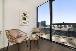 two chairs and a table in a room with a window at Impeccably Styled 2-bedroom CBD Apartment in Melbourne