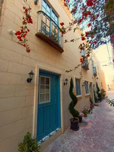 IŻ-ŻEBBUĠA BOUTIQUE SUITES في Żebbuġ: مبنى عليه باب ازرق وعليه ورد