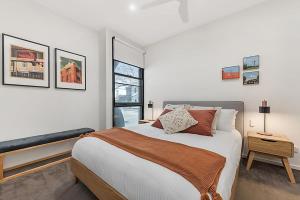 a white bedroom with a bed and a window at Beautiful 2-Storey Unit with Balcony near Smith St in Melbourne