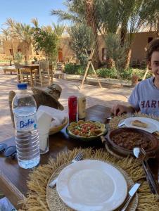 un hombre sentado en una mesa con platos de comida en Zagora Oasis Lodge en Zagora