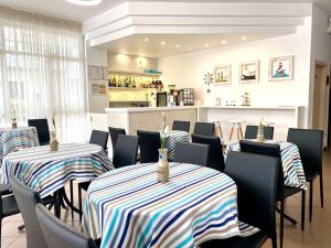リミニにあるHotel Belmarの三台のテーブルと椅子(縞模様のテーブルクロス付)が備わるレストラン