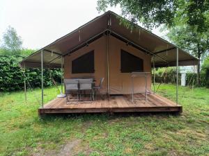 a tent with a table and chairs on a deck at Camping Onlycamp du Moulin in Clisson