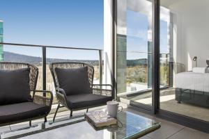 1 dormitorio con 2 sillas y 1 cama en el balcón en Central 2-Bed with Gym, BBQ & Stunning Views en Canberra
